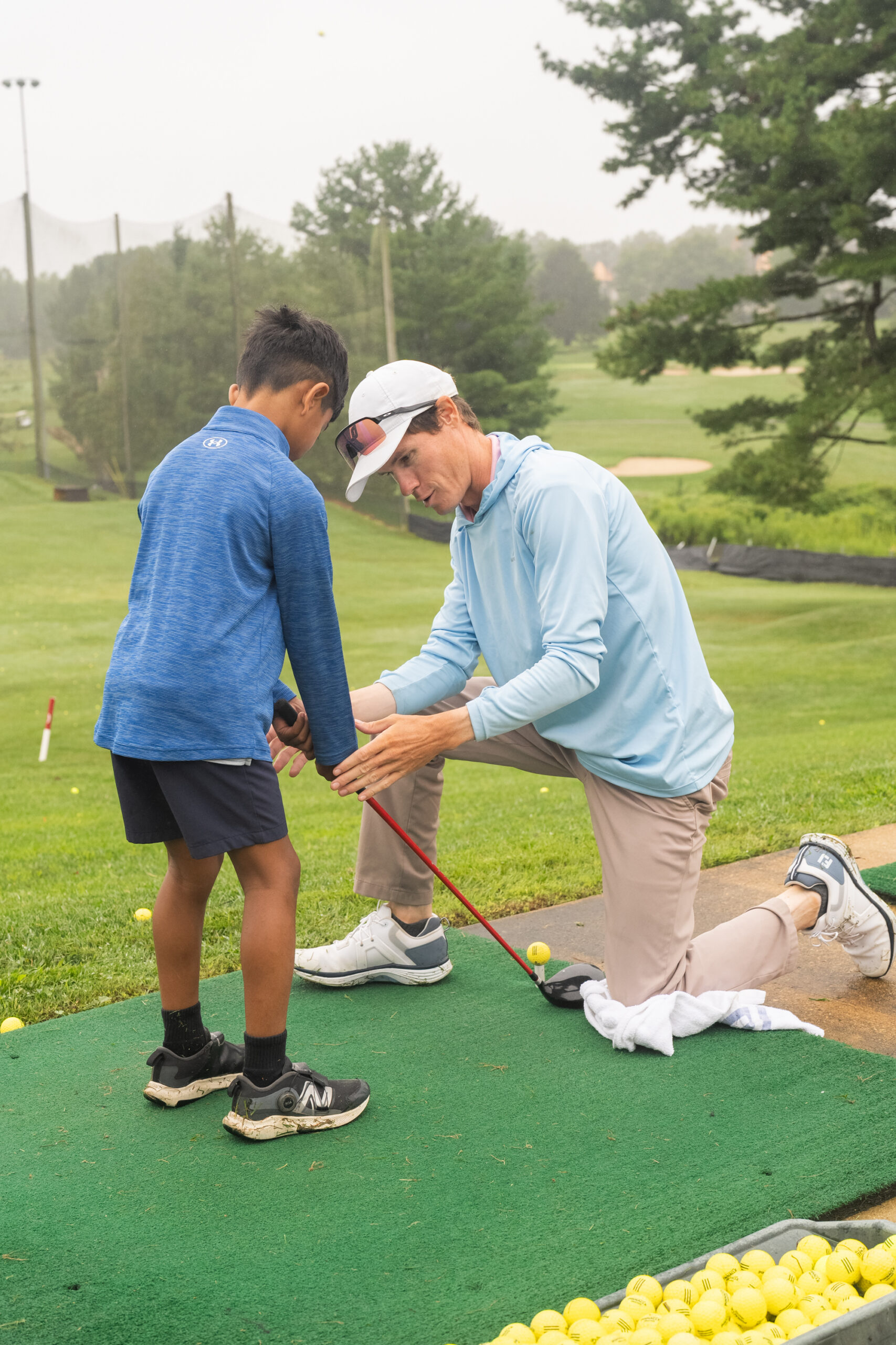 Man instructing a child on how to swing a golf club.