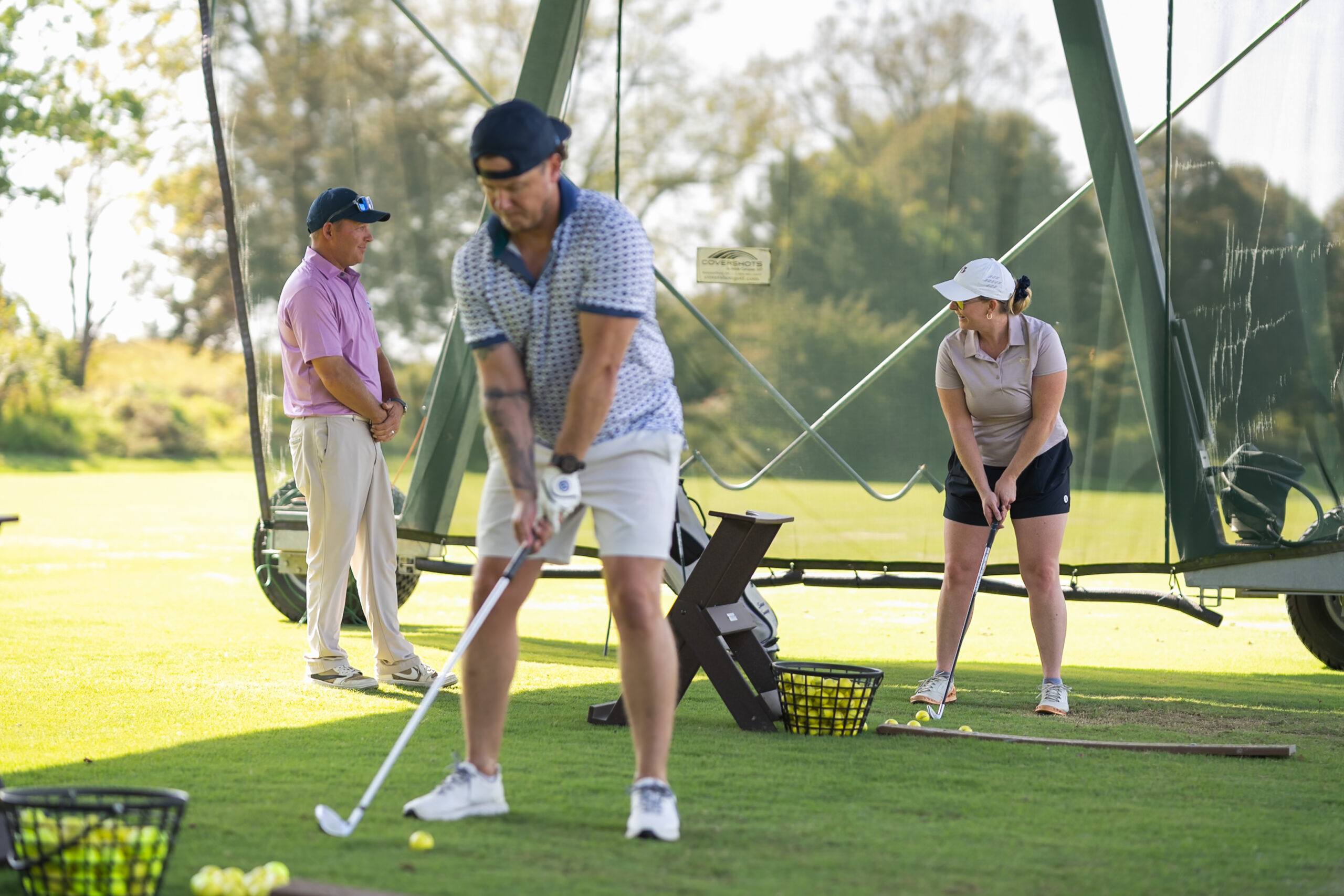 People playing golf on a driving range.