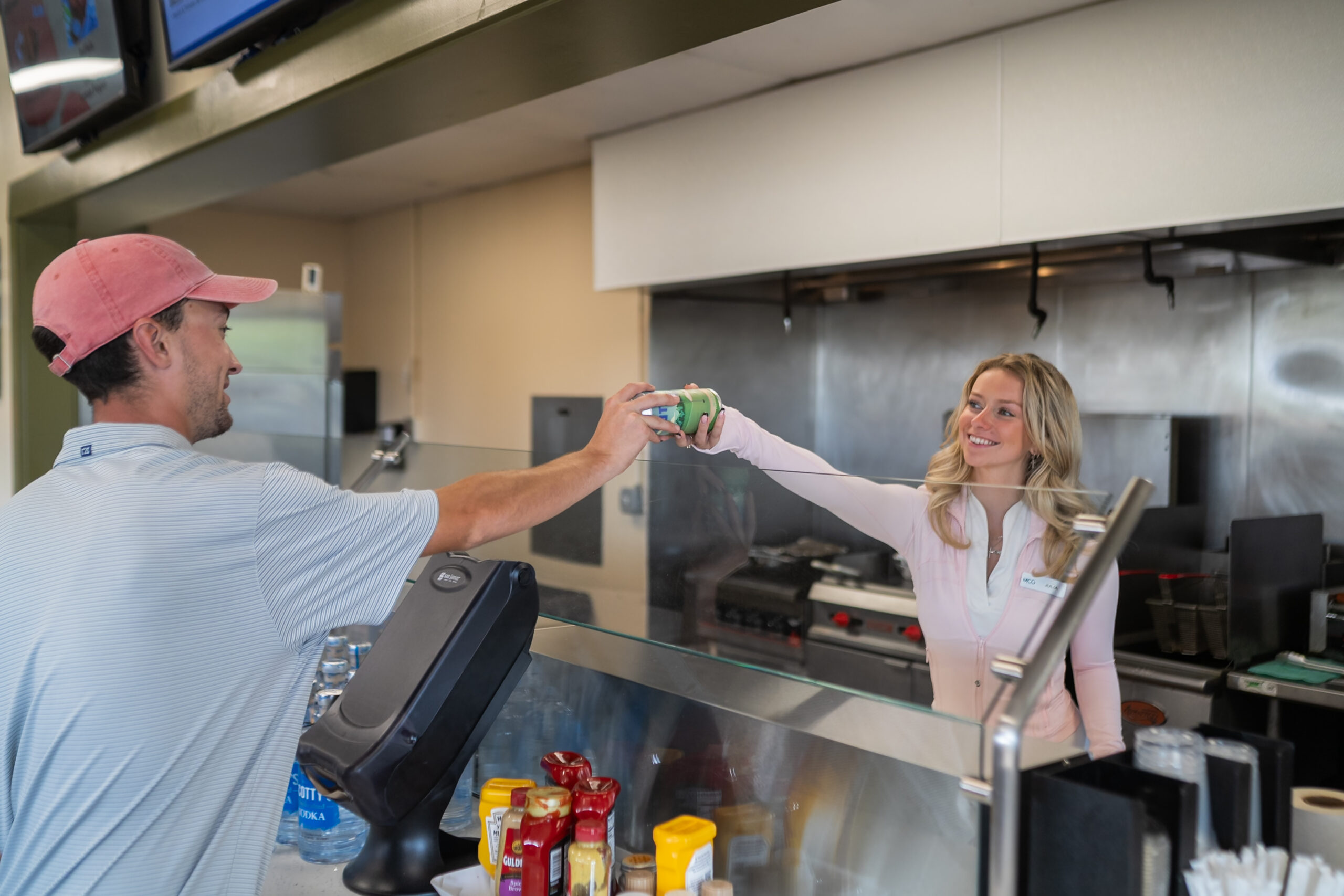 Woman handing a man a canned beverage.